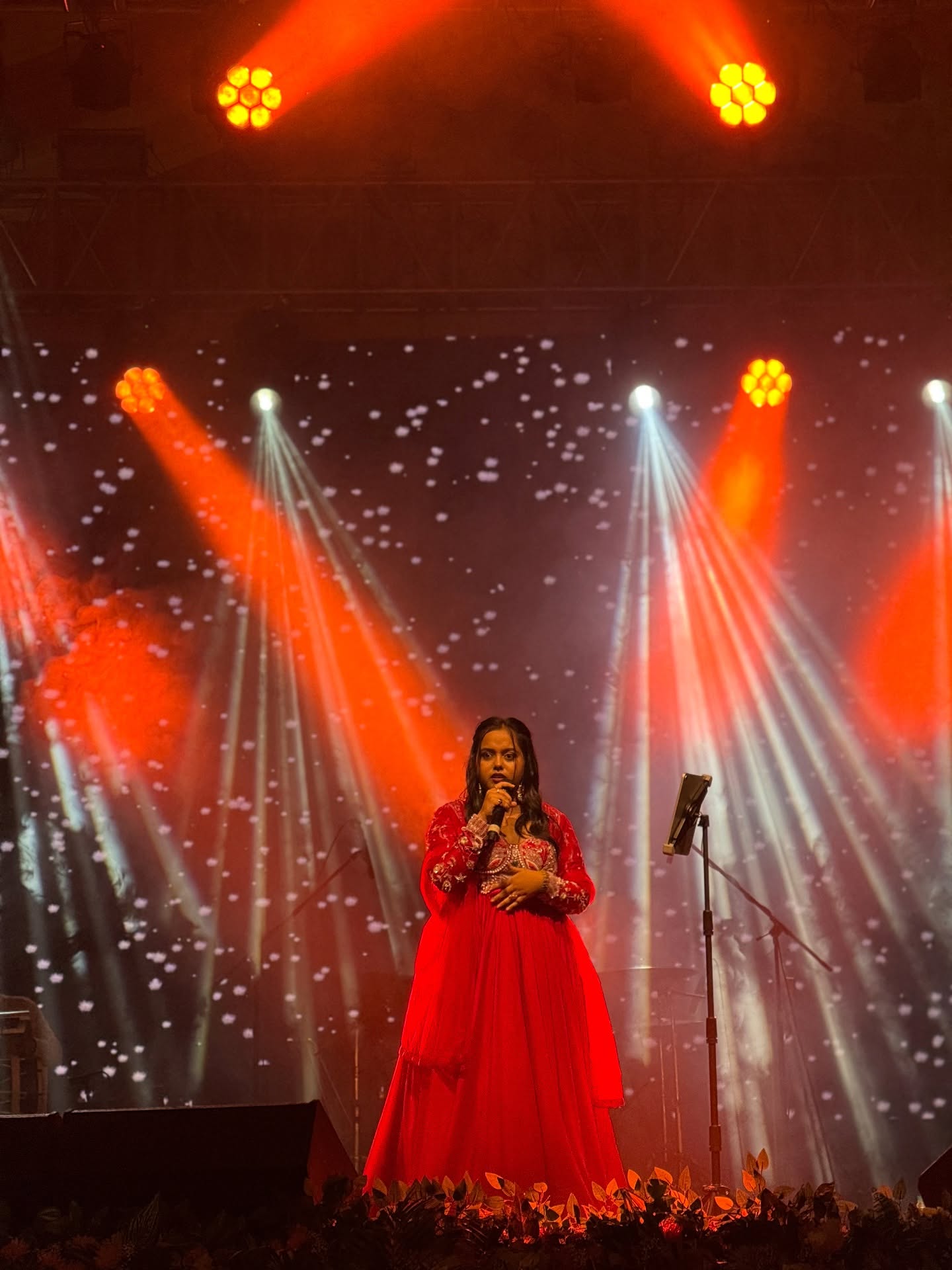 Singer performing under red and white stage beams